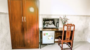 A compact kitchen with a wooden wardrobe, a refrigerator, a chair, and a small table. - Lucky Star hotel (Da Nang)