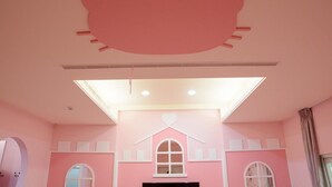 A pink-themed room with a large window, a flat-screen TV, and a ceiling light fixture. - ANKES Hostel (Hengchun)