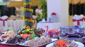 Une table de buffet proposant une variété de plats, notamment des fruits, des légumes et des plats de viande.