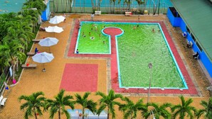 Vue aérienne d’un complexe sportif comprenant un terrain de basket-ball, un terrain de football et une piscine.