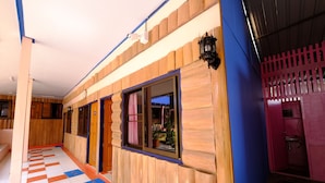 Un couloir d’hôtel avec des lambris en bois, des carreaux de sol à motifs et un espace salle de bain visible, comprenant un lavabo et des toilettes.