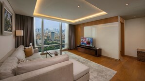 A modern living room with a large window, a sofa, a coffee table, and a TV. - Lotte The Residence (Hanoi)