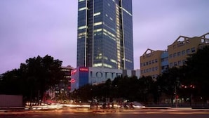 A tall, modern skyscraper with a reflective glass facade, prominent signage, and a distinctive architectural design. - Lotte The Residence (Hanoi)
