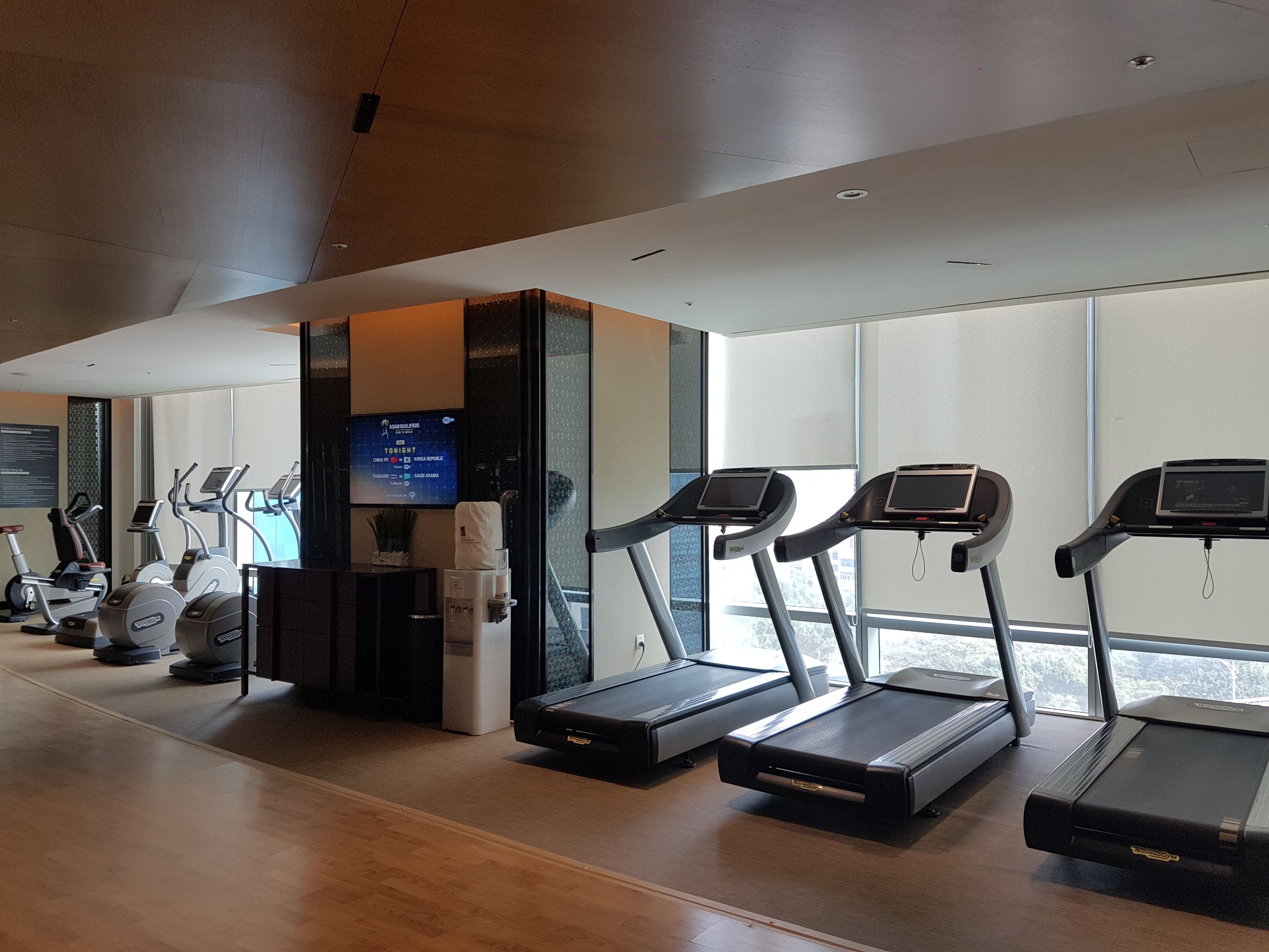 A gym with treadmills, ellipticals, and a water fountain.