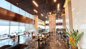 A spacious restaurant with high ceilings, large windows, and a modern interior design. - Lotte The Residence (Hanoi)
