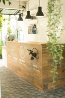 A reception desk with a wooden finish and a clock indicating check-in, check-out, breakfast, and pool hours.