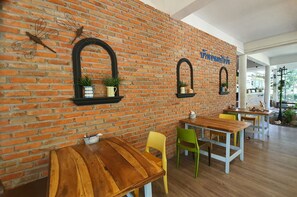 Een restaurant met bakstenen muren, houten tafels en kleurrijke stoelen.