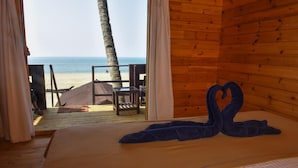 A wooden room with a bed, a view of the beach, and a palm tree. - Agonda Paradise (Canacona)