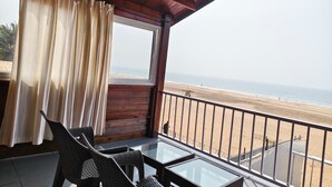 A balcony with a view of the beach, wooden ceiling, and a table with chairs. - Agonda Paradise (Canacona)