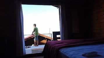 A room with a bed, a wooden desk, and a window with curtains.