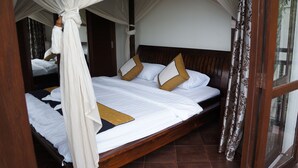 A four-poster canopy bed with white linens and gold accents, a wooden headboard, and a view through a glass door. - Tropicana Beach Villa at  VIP Resort (Rayong)
