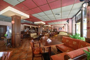 Un restaurante con mobiliario de madera, una zona de bar y un ventanal grande.