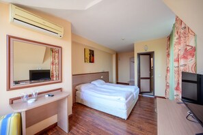 Une chambre d’hôtel comprenant un lit, un bureau avec un miroir, une télévision et une armoire.