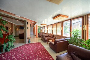 A spacious lobby with a red carpet, leather sofas, and large windows with blinds. - Hotel Royal Beach (Varna)