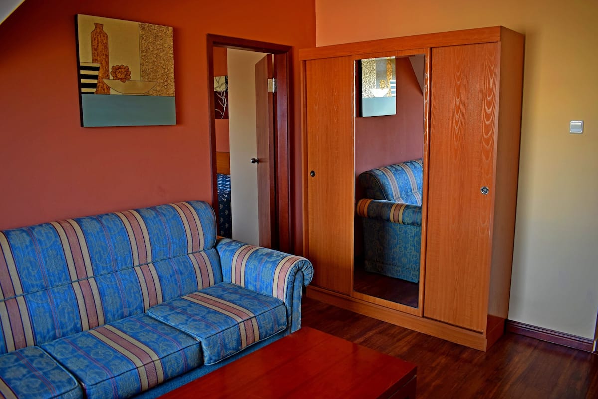 A room with a sofa, a wardrobe, and a painting on the wall.