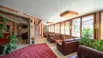 A spacious lobby with a red carpet, leather sofas, and large windows with blinds.