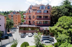 Un hotel de varios pisos con un patio central, zona de estacionamiento y zonas verdes circundantes.