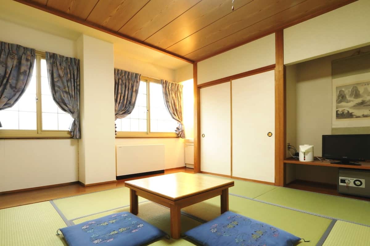 A traditional Japanese room with tatami flooring, a low wooden table, and two cushions.