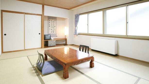 A traditional Japanese room with tatami flooring, a wooden table, a chair, a television, a heater, and a shoji screen. - Hakuba Tsugaike Sunrise TANNE (Otari)