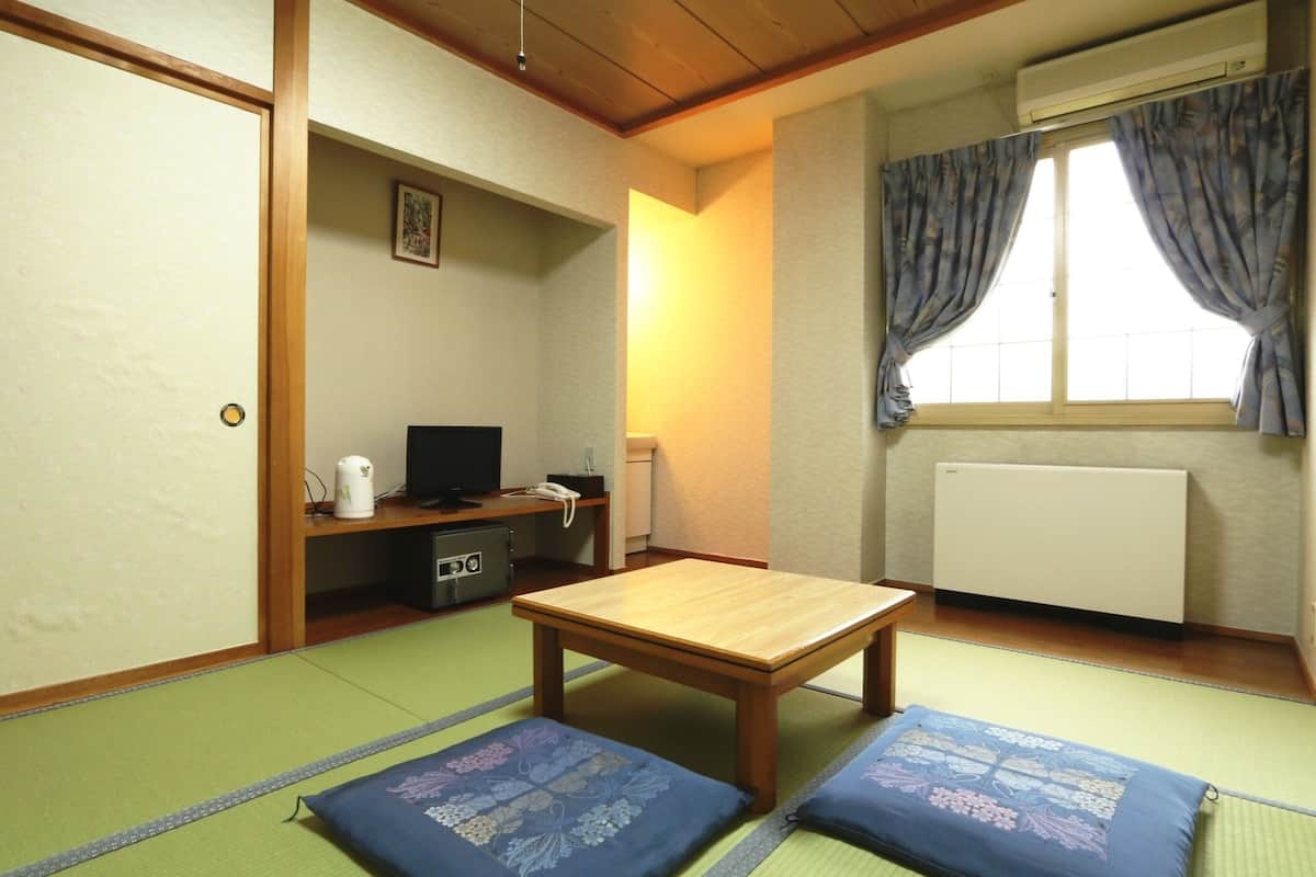 A traditional Japanese room with tatami flooring, a wooden table, and cushions.