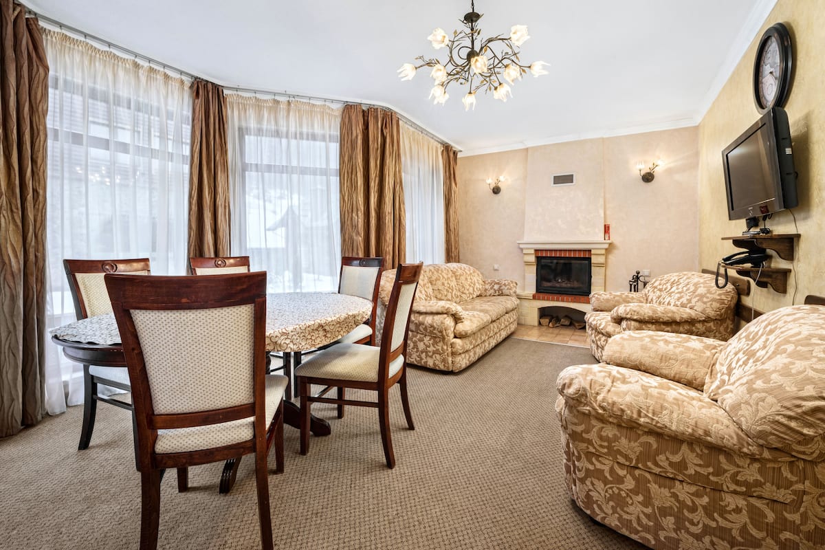 A living room with a dining table, chairs, sofas, a fireplace, and a television.