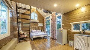 A cozy room with a bed, a small kitchenette, a window, and a ceiling fan. - Greenview Resort (Nakhon Nayok)