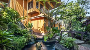 A courtyard with a small pond, lush greenery, and a building with balconies. - Greenview Resort (Nakhon Nayok)