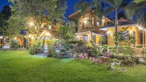 A two-story wooden house with a well-maintained garden and a welcoming sign. - Greenview Resort (Nakhon Nayok)