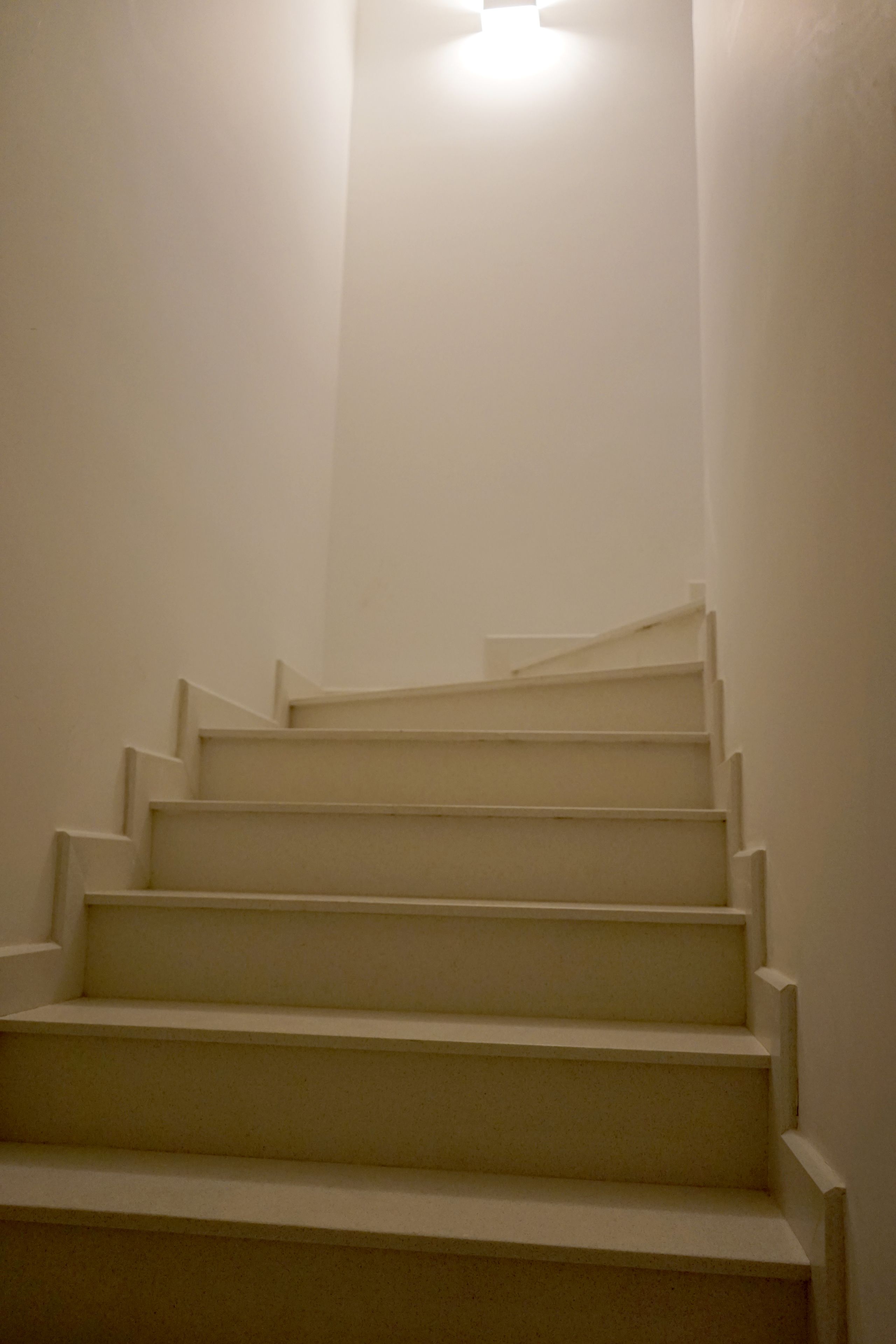 Een reeks witte trappen die omhoog leiden in een schemerig gebied.