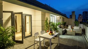 An outdoor patio area with a dining table, chairs, a sofa, and potted plants. - La Cigale Residence (Ho Chi Minh City)