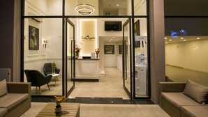 A hotel reception area with a modern design, featuring a reception desk, seating area, and a water dispenser. - La Cigale Residence (Ho Chi Minh City)