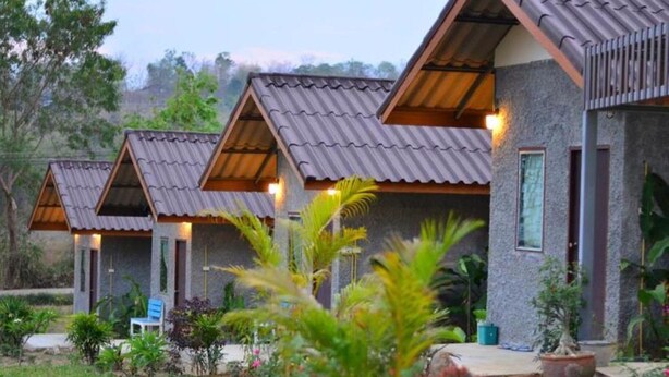 Eine Reihe von bungalows mit geneigten Dächern und Steinmauern, umgeben von üppiger Vegetation.