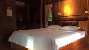 Ein hölzernes Bett in einem Blockhaus-Zimmer mit Kopfteil und einem Vorhangfenster.
