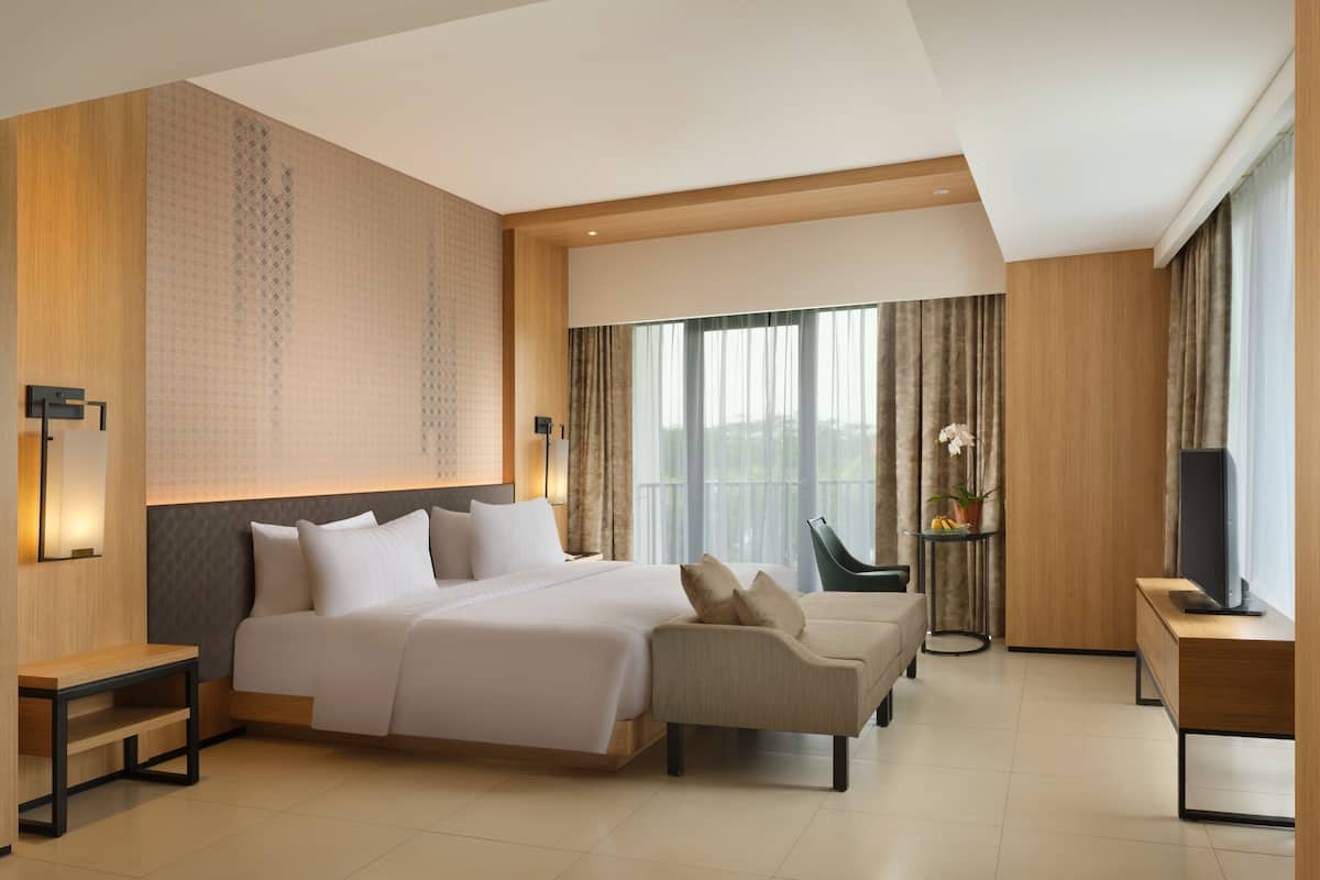 Een moderne hotelkamer met een groot bed, een bank, een televisie en een tafeltje.