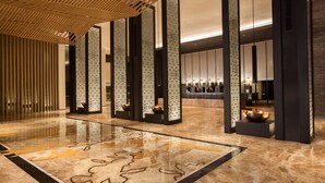 Un hall d’entrée spacieux, doté d’un sol en marbre poli, de hauts panneaux décoratifs et d’un espace d’accueil au design moderne.