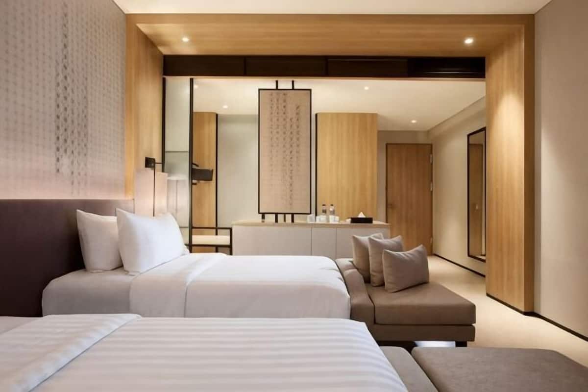 Een moderne hotelkamer met twee bedden, een bank, een grote spiegel en een houten plafond.