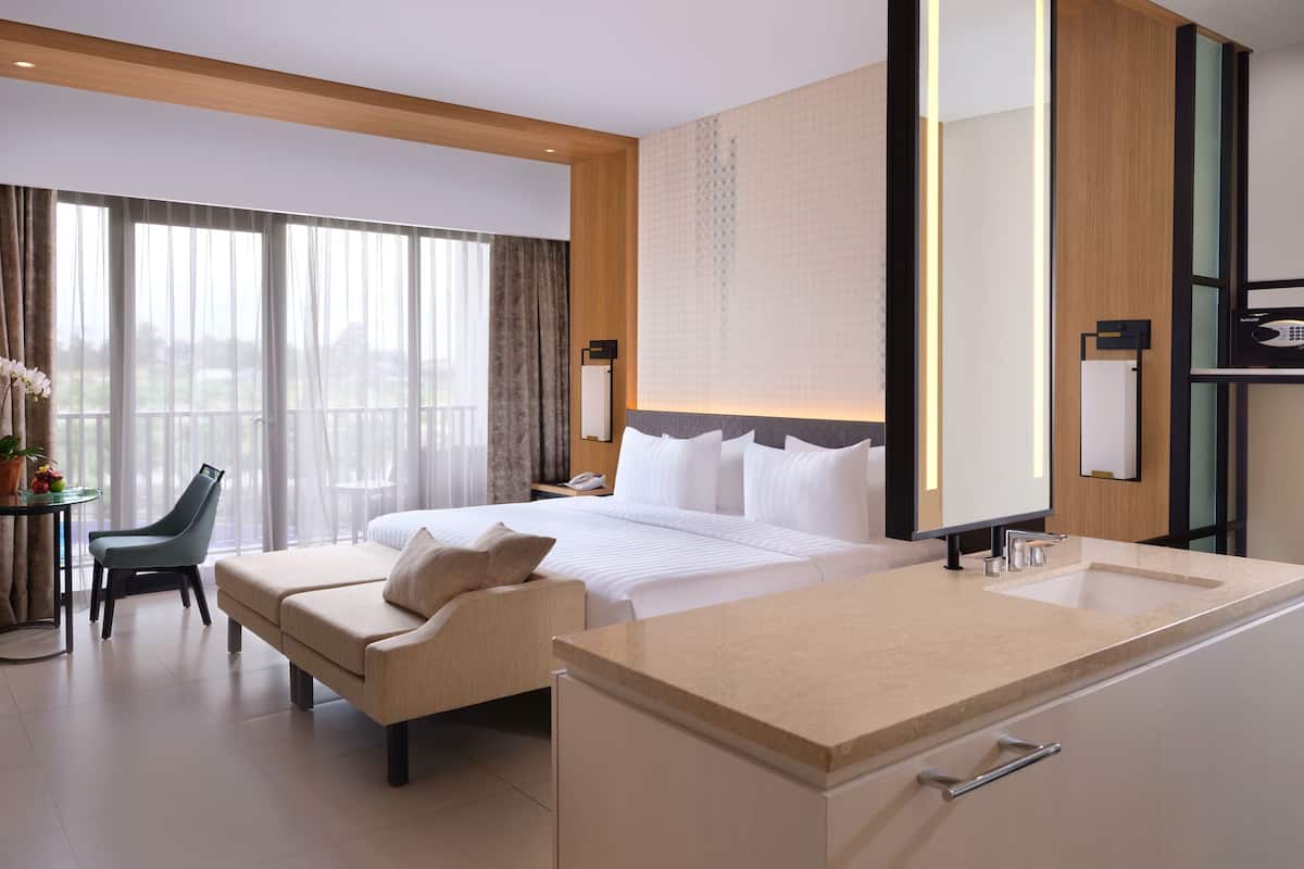 Een moderne hotelkamer met een groot bed, een zithoek, een bureau en een badkamer.
