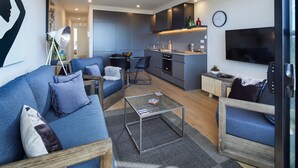 Ein modernes Wohnzimmer mit einer Couch, Sesseln, einem Couchtisch und einem Fernseher.