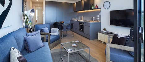 A modern living room with a sofa, chairs, a coffee table, and a TV.