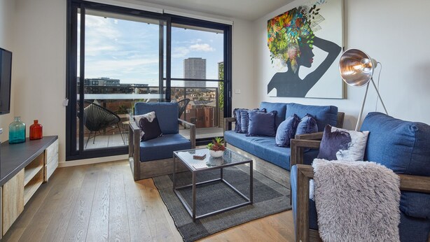 Ein modernes Wohnzimmer mit einem blauen Sofa, einem Couchtisch und einem großen Fenster mit Blick auf die Stadt.