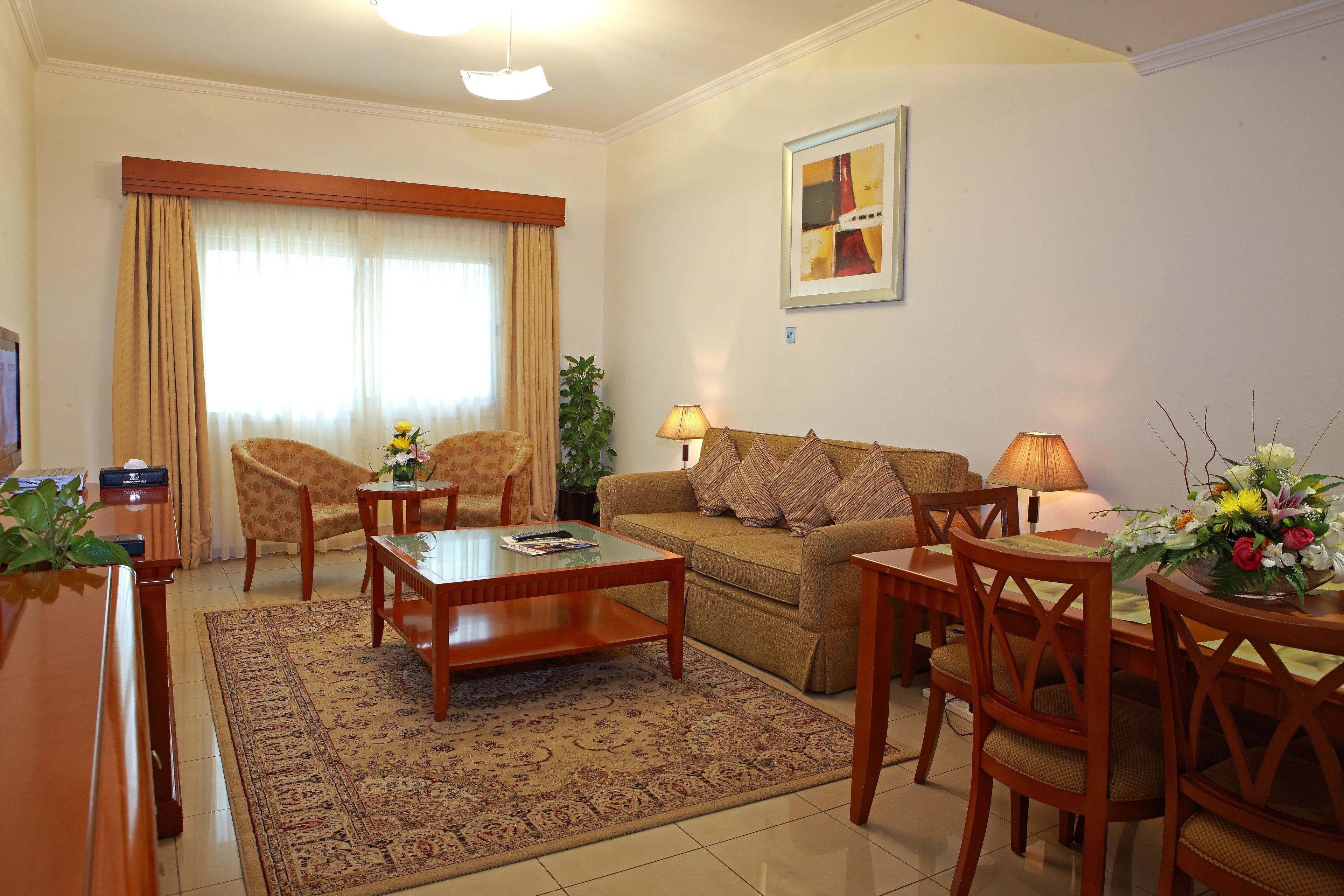 Una sala de estar con un sofá, sillones, una mesa de centro, un televisor y una lámpara.