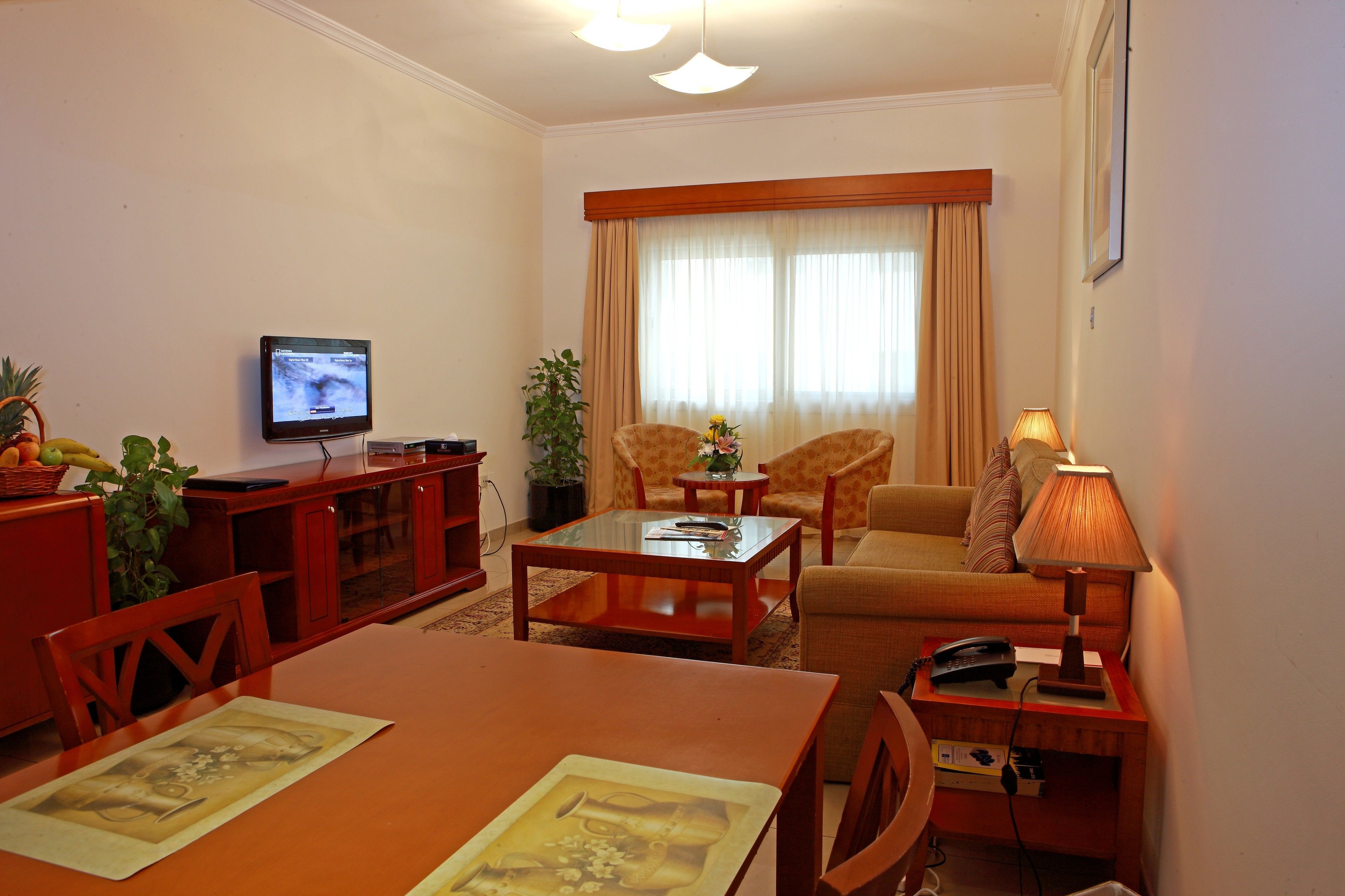 Una sala de estar con televisor, una mesa de comedor, un sofá y una lámpara.