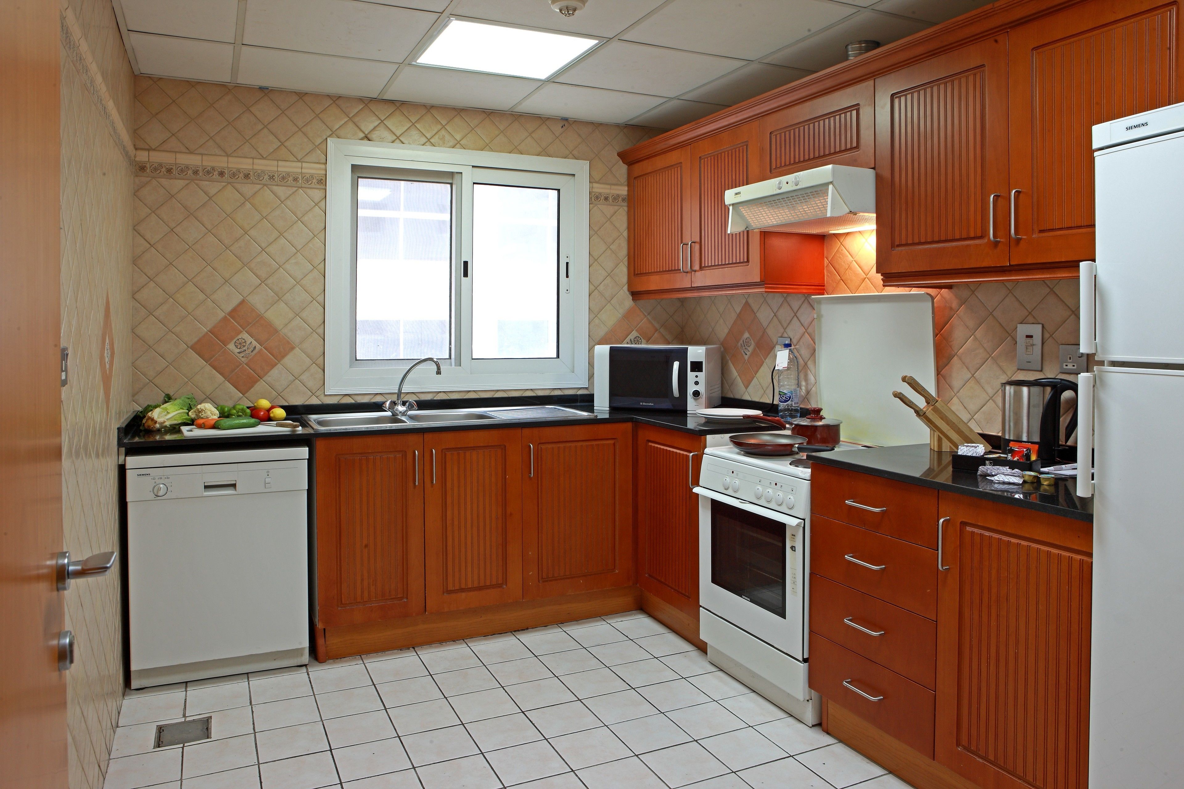 A kitchen with wooden cabinets, a dishwasher, a microwave, an oven, and a refrigerator.