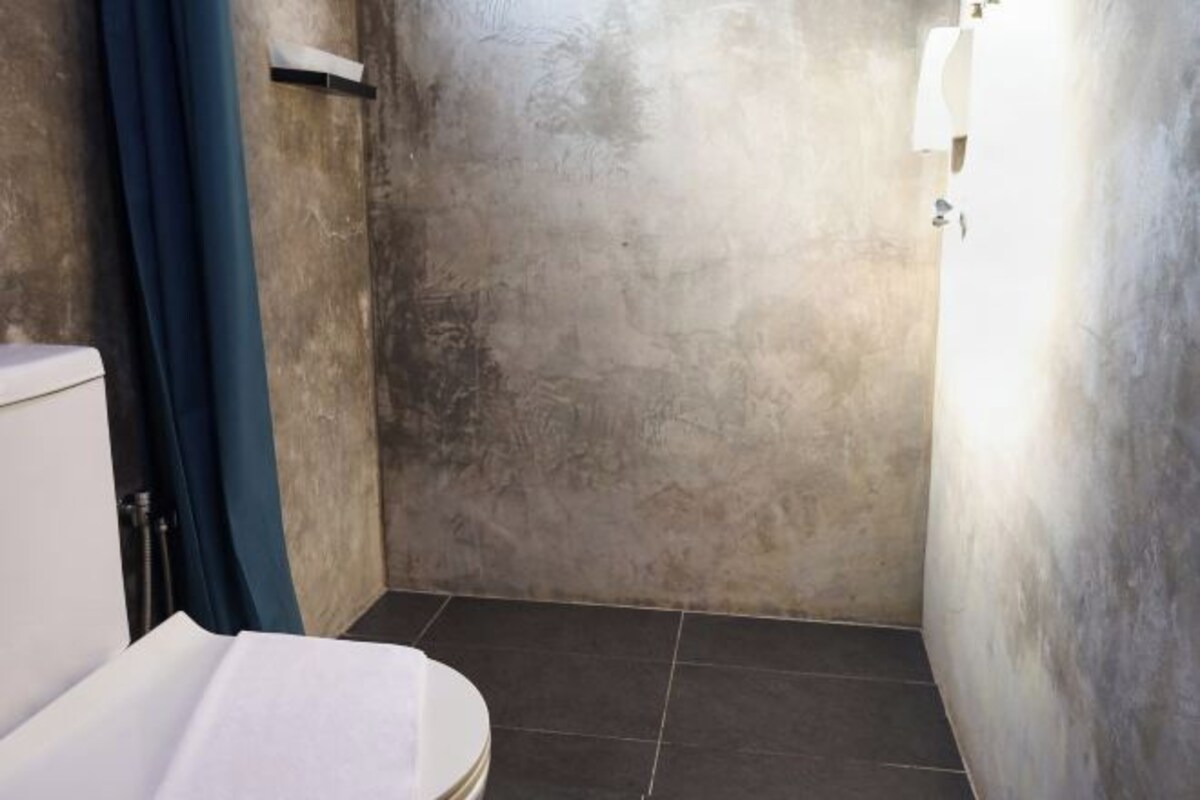 A small bathroom with a toilet, a towel rack, and a shower area.