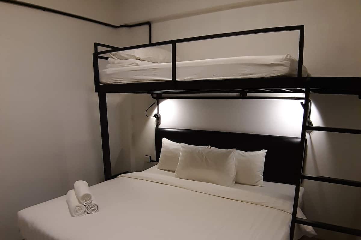 Ein Stockbett mit weißer Bettwäsche und einem ordentlich bezogenen Unterbett.