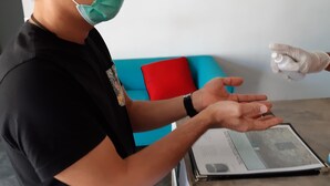 Eine Person mit schwarzem Hemd und Mütze streckt die Hand aus.