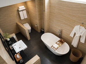 Ein modernes Badezimmer mit einer freistehenden Badewanne, einem Waschbecken, einer Toilette und einem Handtuchhalter.