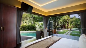 Una habitación de hotel moderna con una cama grande, un escritorio y vistas a una piscina y un jardín.