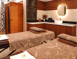 A hotel room with two beds, a wooden wardrobe, a stone accent wall, a sink, and a mirror. - Del Cielo Villa Jimbaran (Jimbaran)