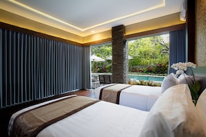 A hotel room with two beds, a stone pillar, a view of a pool, and a dining area with umbrellas. - Del Cielo Villa Jimbaran (Jimbaran)